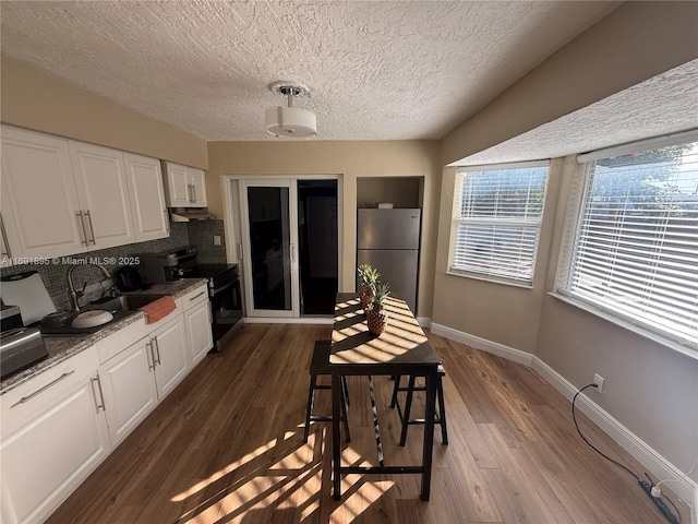 kitchen with white cabinets, appliances with stainless steel finishes, sink, backsplash, and stone counters