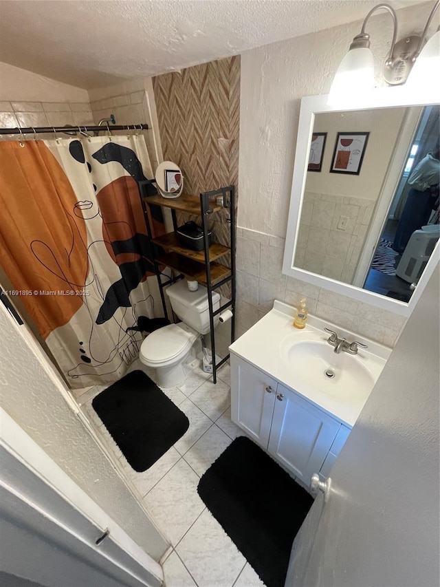 bathroom with toilet, tile patterned flooring, tile walls, a textured ceiling, and vanity