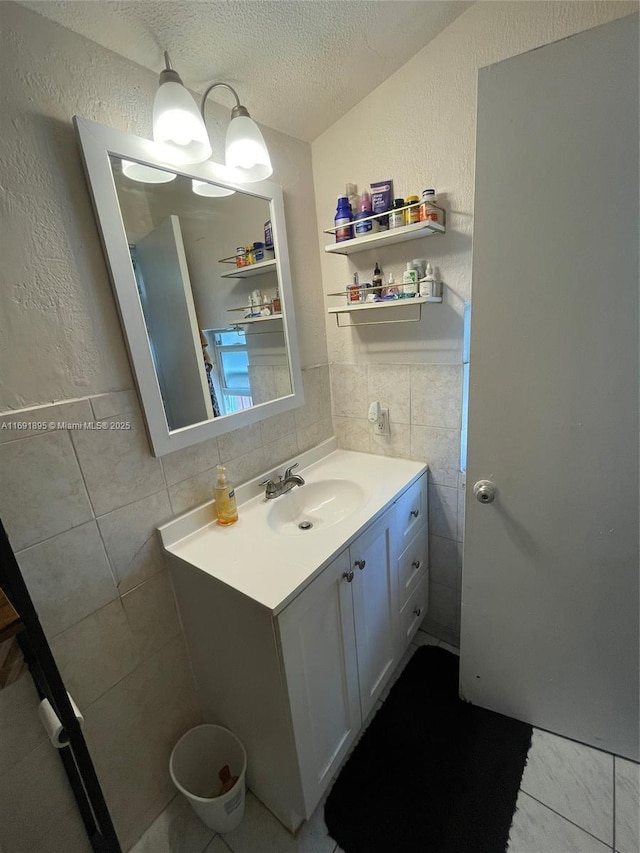 bathroom with a textured ceiling, tile walls, tasteful backsplash, and vanity