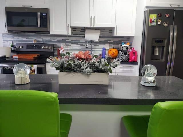 kitchen with backsplash, white cabinets, and appliances with stainless steel finishes