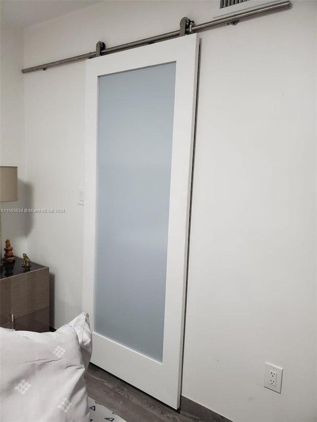 bedroom featuring a barn door and dark hardwood / wood-style floors