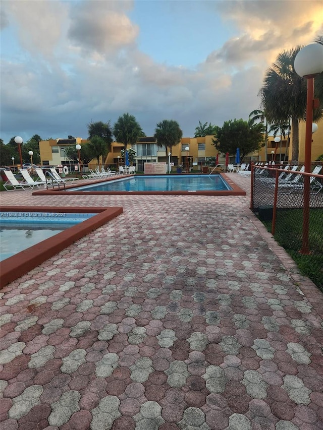 pool at dusk with a patio area