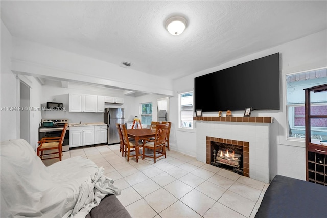 tiled living room with a tile fireplace, sink, and a textured ceiling