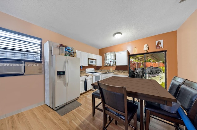 kitchen featuring cooling unit, light hardwood / wood-style floors, a textured ceiling, white appliances, and white cabinets