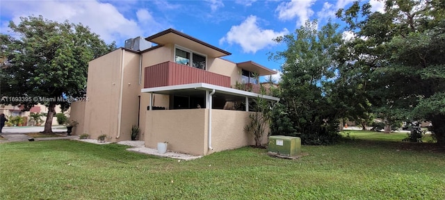 view of home's exterior with a yard and a balcony