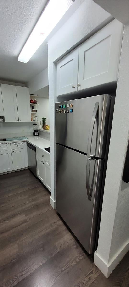 kitchen featuring white cabinets, dark hardwood / wood-style floors, a textured ceiling, and appliances with stainless steel finishes