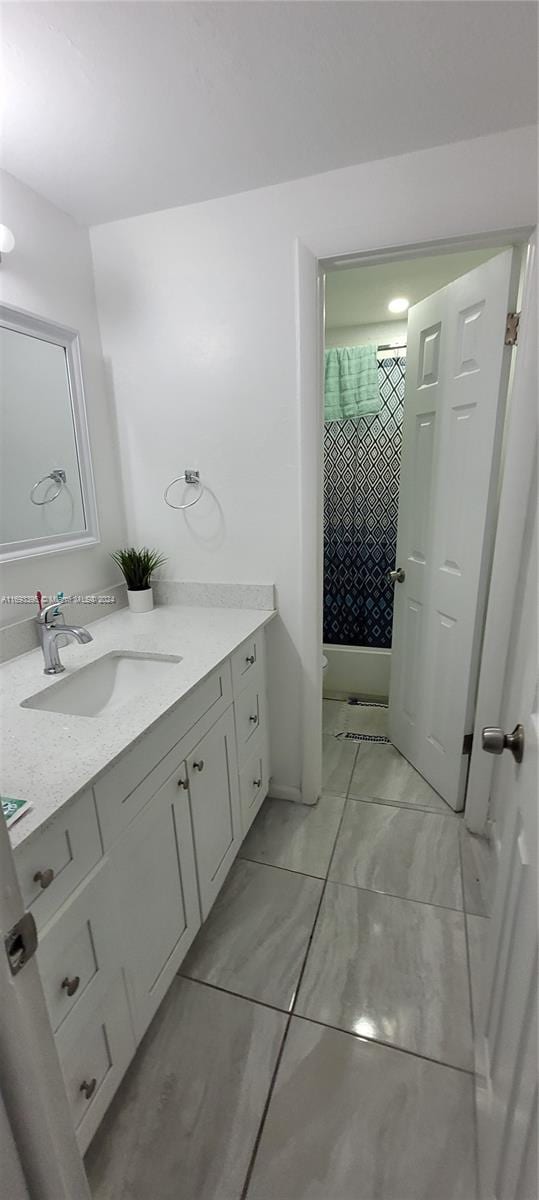 bathroom featuring tiled shower and vanity