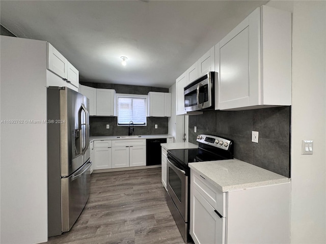 kitchen with white cabinetry, sink, stainless steel appliances, hardwood / wood-style floors, and decorative backsplash