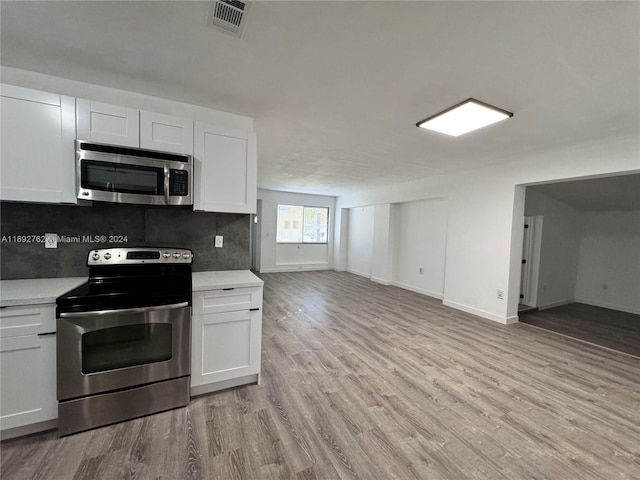 kitchen featuring decorative backsplash, white cabinetry, light hardwood / wood-style flooring, and stainless steel appliances