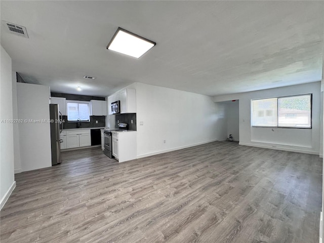 unfurnished living room featuring light hardwood / wood-style floors and sink