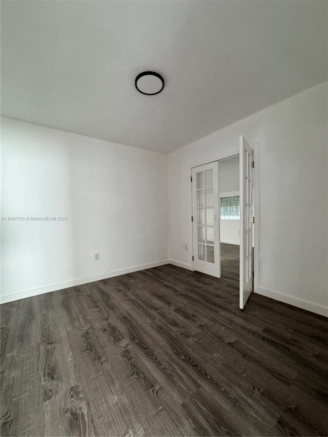 empty room with dark hardwood / wood-style floors and french doors