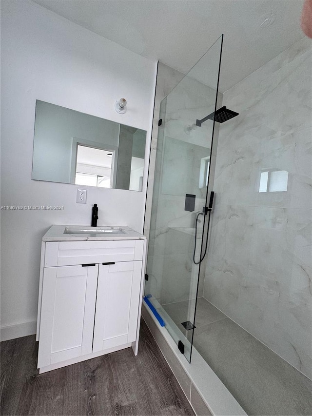 bathroom with hardwood / wood-style floors, vanity, and tiled shower