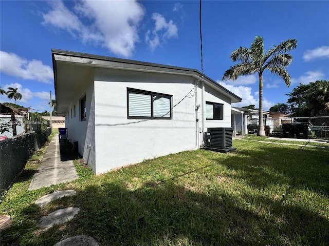 view of side of home featuring central AC and a yard