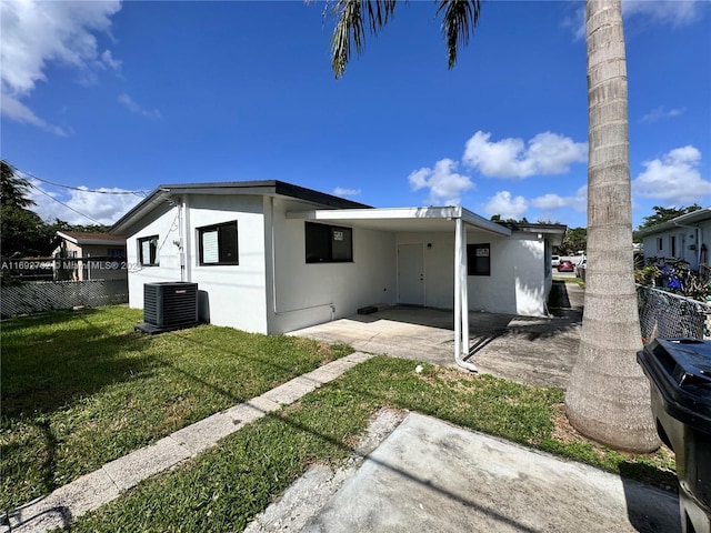 back of property with central AC unit, a patio area, and a lawn