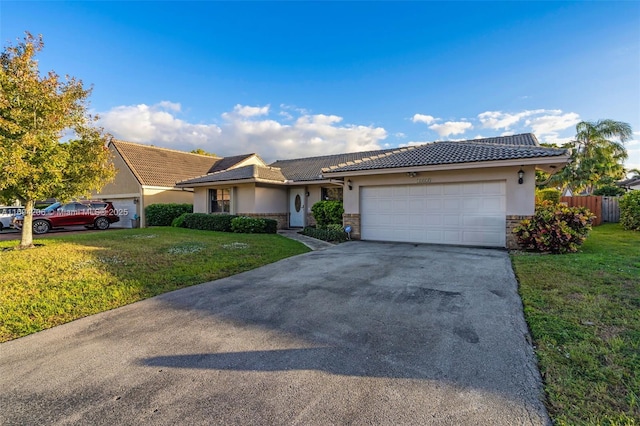 ranch-style home featuring a front yard, driveway, stucco siding, stone siding, and a garage