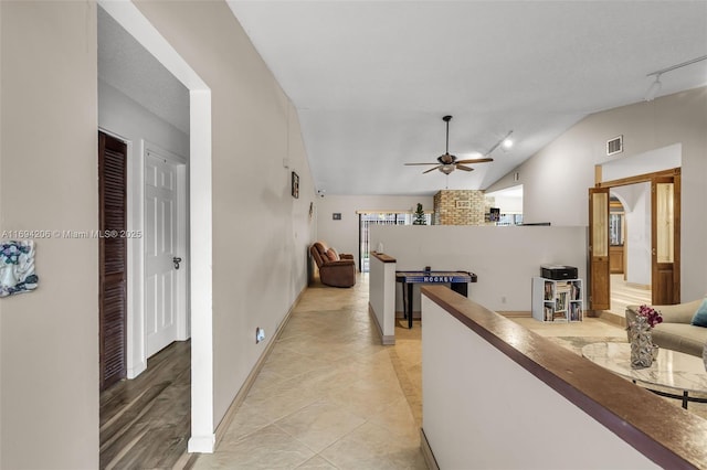 corridor featuring visible vents, lofted ceiling, an upstairs landing, rail lighting, and light tile patterned flooring