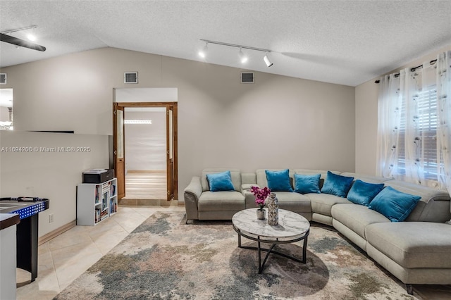 living room featuring light tile patterned floors, visible vents, a textured ceiling, and vaulted ceiling