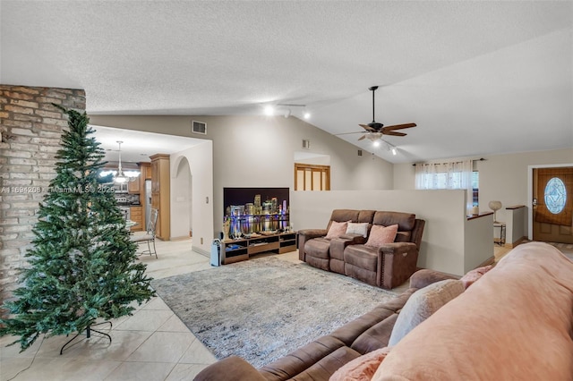 living area featuring visible vents, lofted ceiling, ceiling fan with notable chandelier, light tile patterned flooring, and a textured ceiling