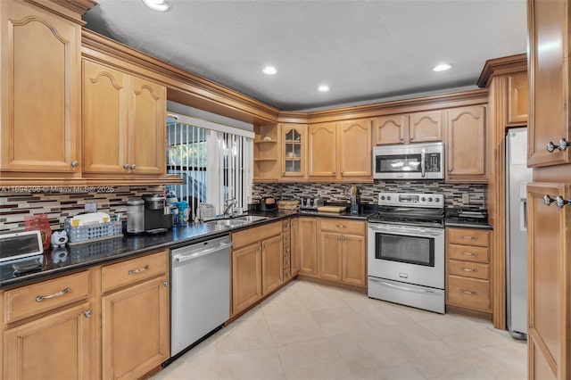 kitchen with a sink, glass insert cabinets, dark countertops, appliances with stainless steel finishes, and decorative backsplash