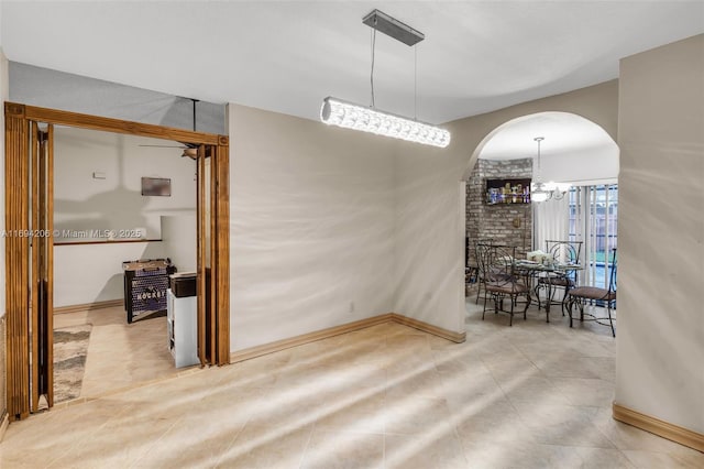 dining room featuring arched walkways, a notable chandelier, tile patterned flooring, and baseboards