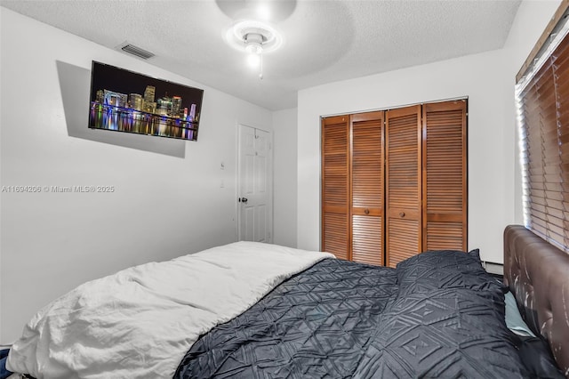 bedroom featuring a closet, visible vents, a textured ceiling, and ceiling fan