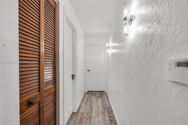 corridor with light hardwood / wood-style floors and a textured ceiling