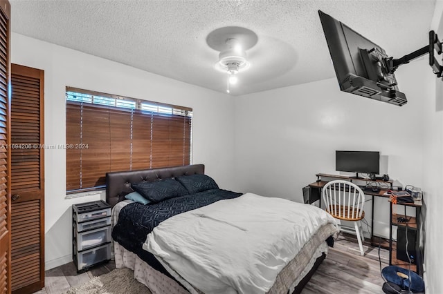 bedroom with a textured ceiling, light hardwood / wood-style floors, and ceiling fan