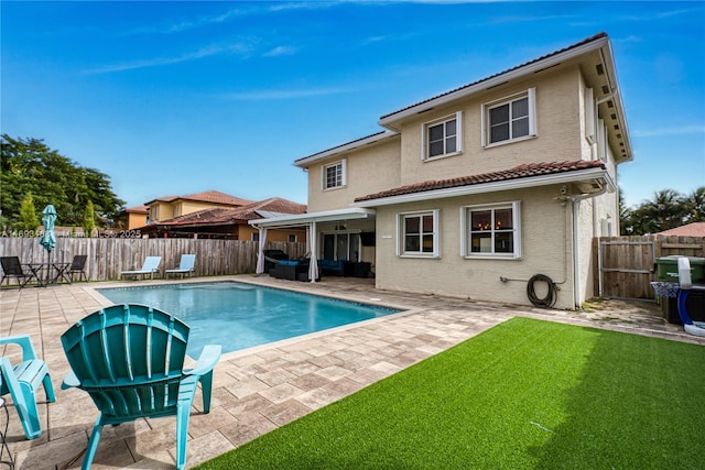 back of house featuring a yard, a fenced in pool, and a patio area