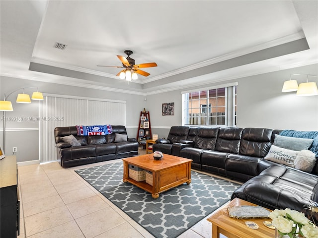 tiled living room with a raised ceiling, ceiling fan, and ornamental molding