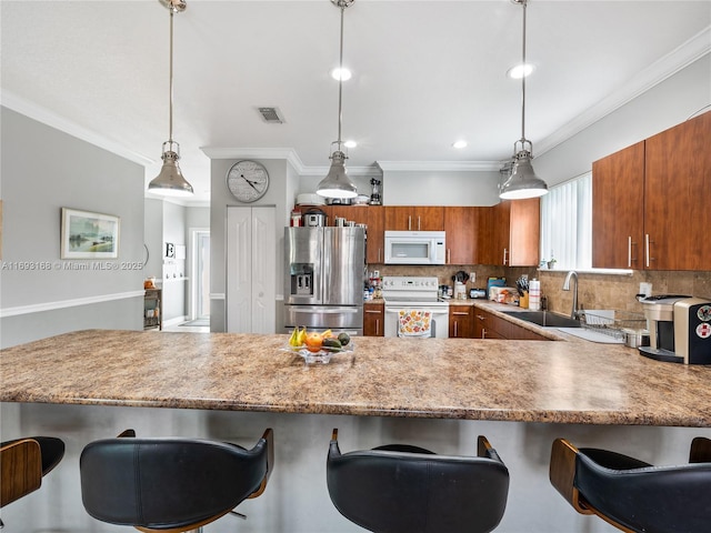 kitchen with a breakfast bar area, sink, pendant lighting, and white appliances