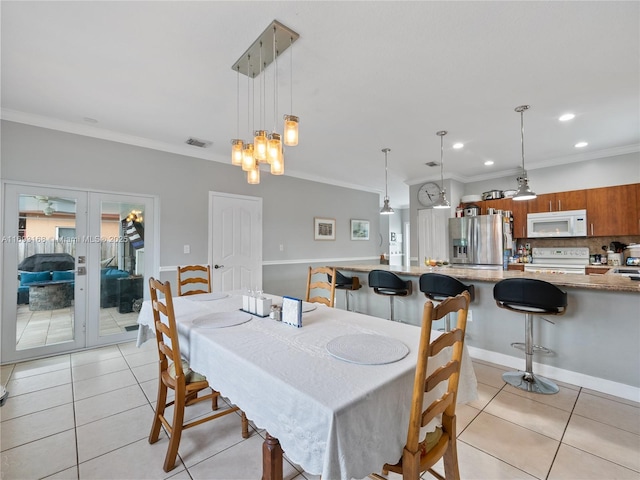 dining room with light tile patterned floors, crown molding, and french doors