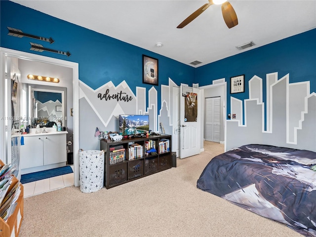 carpeted bedroom with ensuite bath and ceiling fan