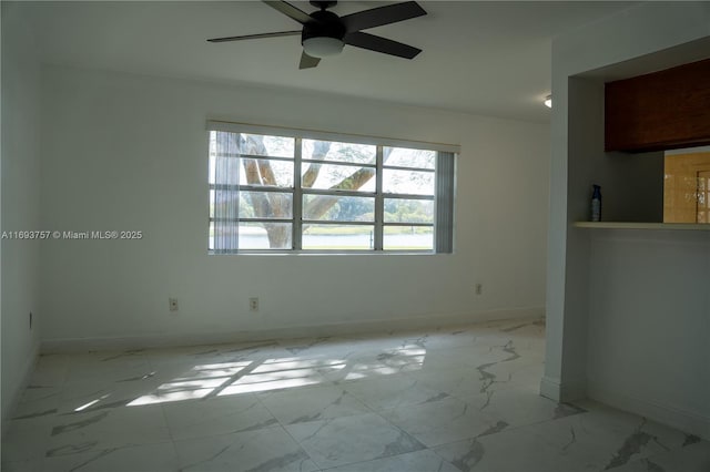 spare room with marble finish floor, a ceiling fan, and baseboards