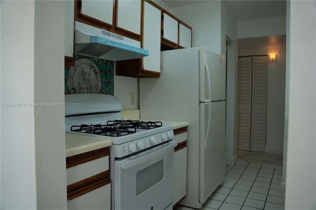 kitchen with under cabinet range hood, gas range gas stove, light countertops, and white cabinetry