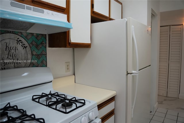 kitchen with under cabinet range hood, white appliances, white cabinets, and light countertops