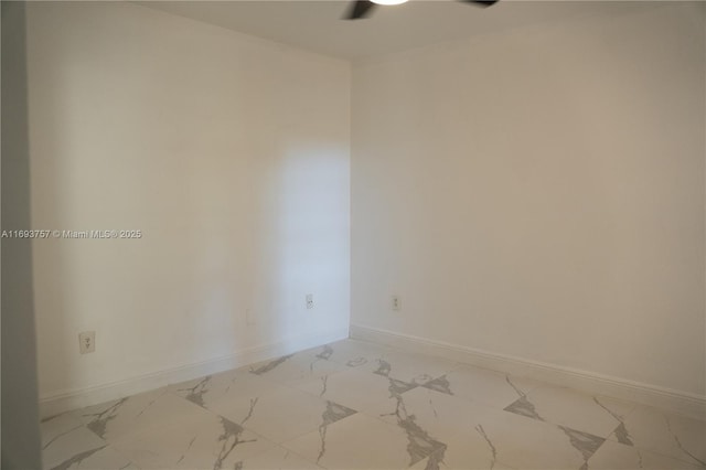 unfurnished room featuring marble finish floor and baseboards