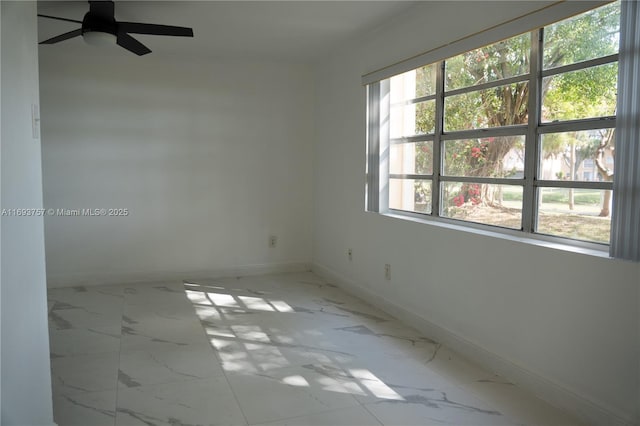 unfurnished room featuring baseboards, marble finish floor, and ceiling fan