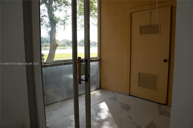 doorway to outside featuring visible vents, a water view, and marble finish floor