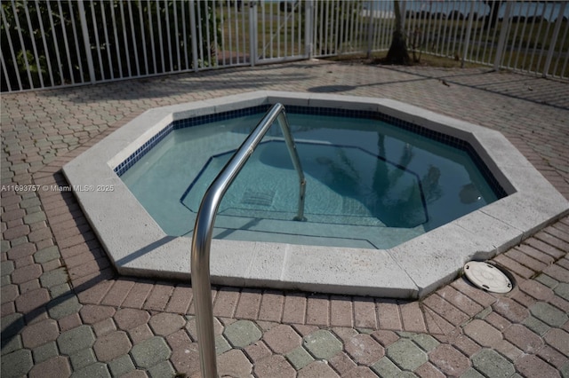 view of swimming pool with an in ground hot tub and fence