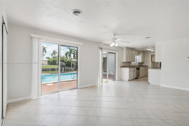 unfurnished living room featuring ceiling fan, sink, and light tile patterned floors