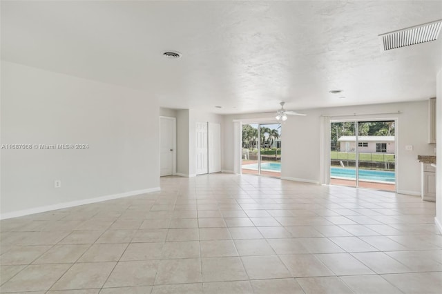 spare room with ceiling fan and light tile patterned flooring