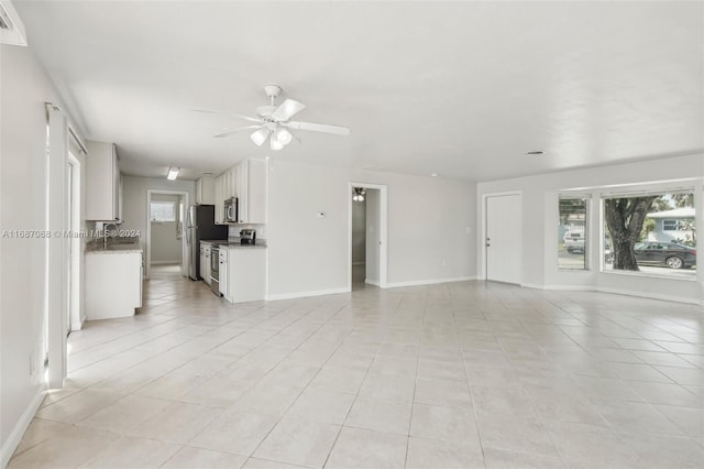 unfurnished living room with ceiling fan, light tile patterned floors, and sink