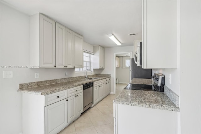 kitchen with white cabinets, sink, light stone countertops, light tile patterned floors, and stainless steel appliances