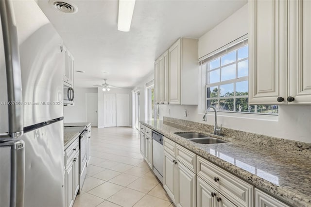 kitchen featuring sink, light stone countertops, appliances with stainless steel finishes, light tile patterned flooring, and white cabinetry