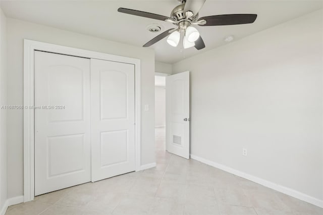 unfurnished bedroom with ceiling fan, a closet, and light tile patterned floors