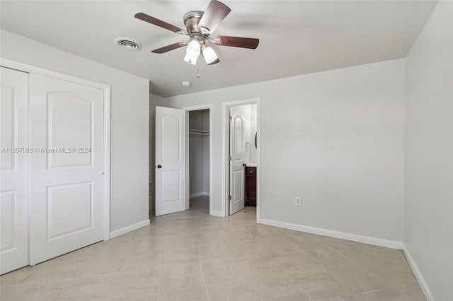 unfurnished bedroom featuring connected bathroom, ceiling fan, and light tile patterned floors