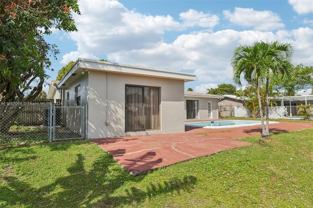 back of property with a yard, a patio, and a fenced in pool