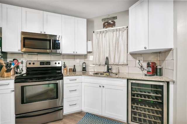 kitchen featuring white cabinets, appliances with stainless steel finishes, wine cooler, and sink