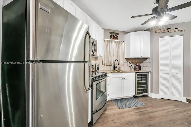 kitchen featuring backsplash, sink, wine cooler, appliances with stainless steel finishes, and white cabinetry