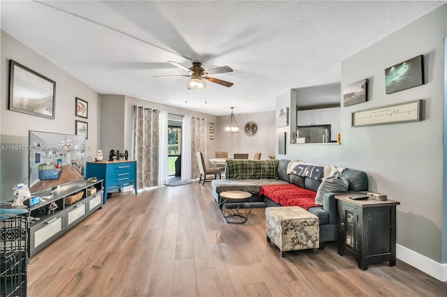 living room with ceiling fan, light hardwood / wood-style flooring, and a textured ceiling